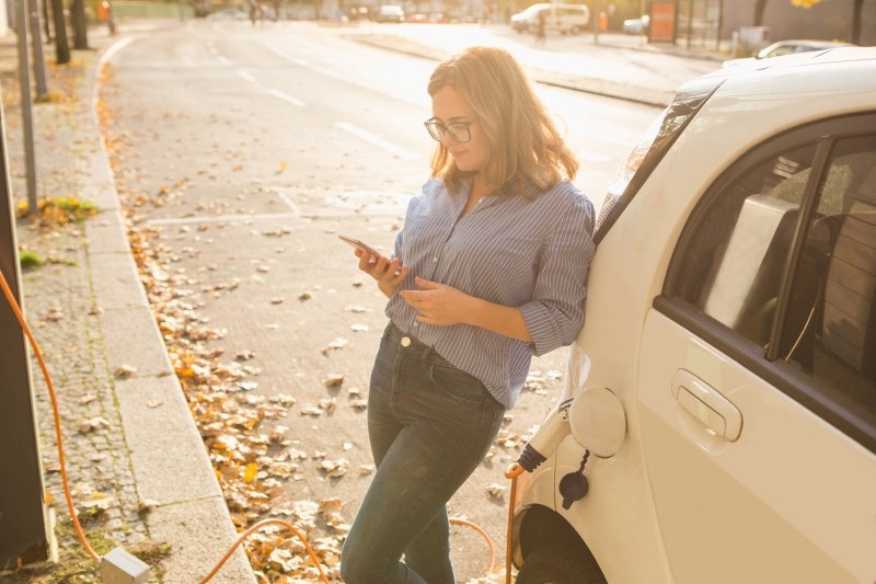 Elektro Auto aufladen Frau wartet