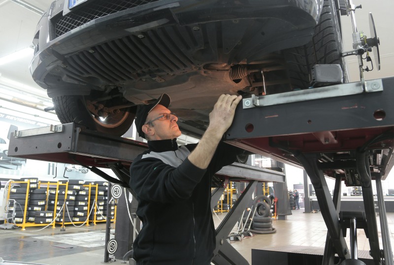Mechatroniker unter Auto, das auf Hebeühne steht